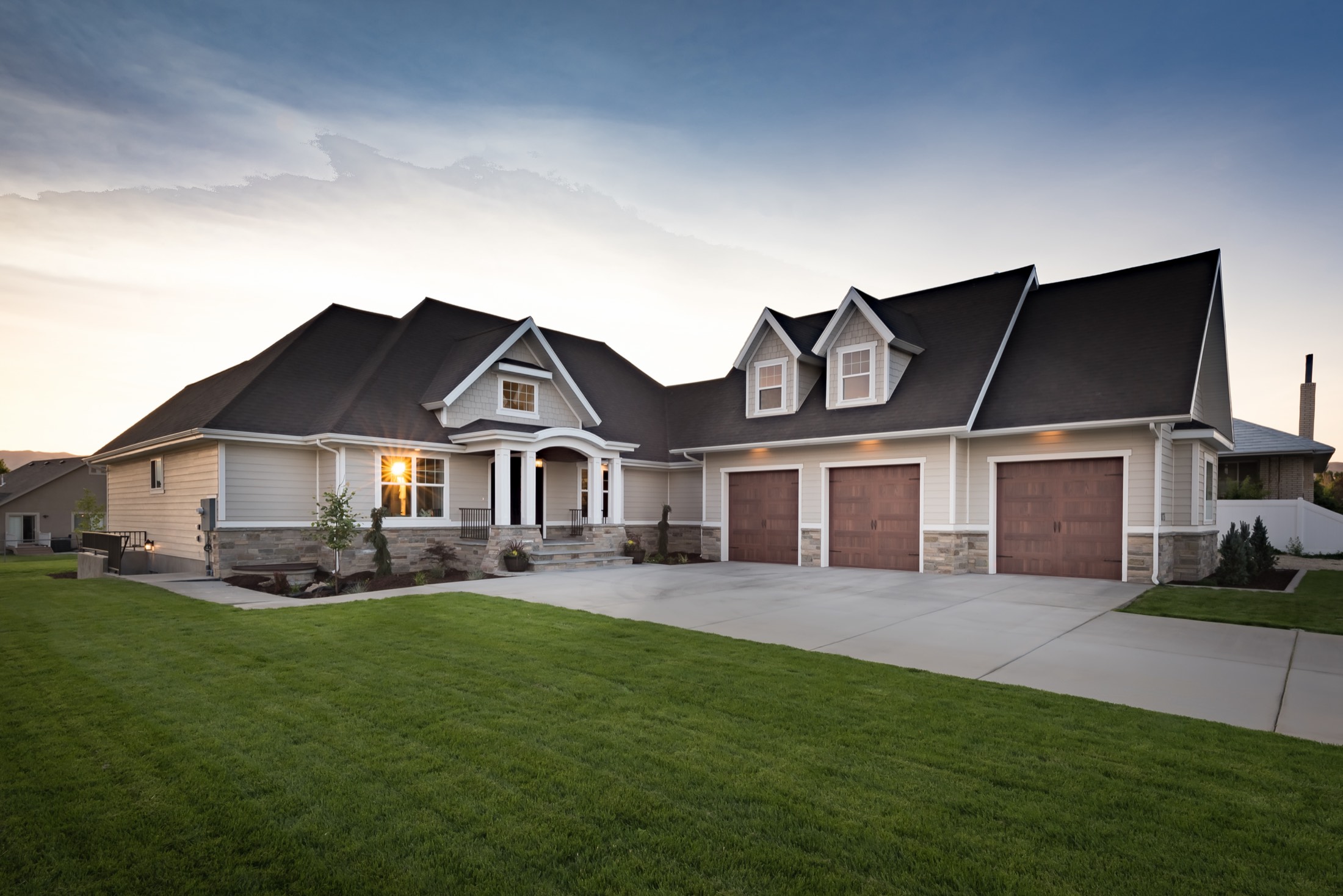 Front elevation at twilight with triple gables and stone wainscot