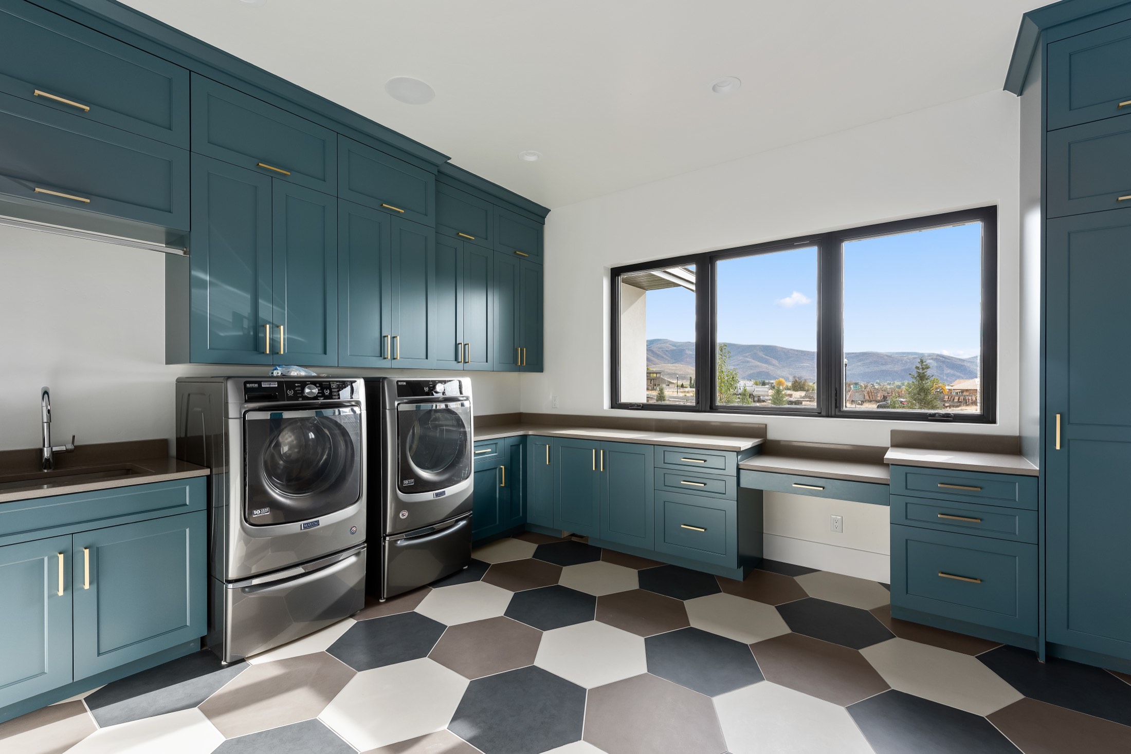 Laundry with blue cabinetry and patterned tile